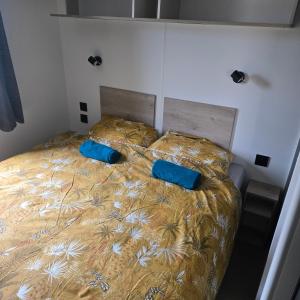 a bed with two blue pillows on top of it at Mobil-home les pieds dans l'eau camping LES DUNES 5"'" in Torreilles +5 photos
