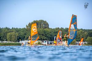 un gruppo di persone che fanno windsurf sull'acqua di Chalëpë 20 całoroczne, komfortowe domki "Tiny House" a Chałupy