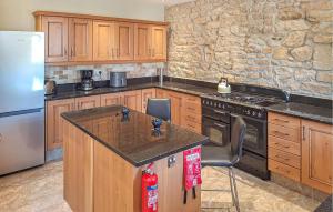 - une cuisine avec des placards en bois et un mur en pierre dans l'établissement Ravissante Maison Bretonne, à Louargat