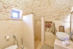 a bathroom with a sink and a toilet in a room at Villa Quattro e Cinque by Villa Plus in San Michele Salentino +22 photos