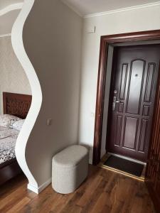 a bedroom with a bed and a stool next to a door at Квартира на березі Дніпра у новому будинку! in Cherkasy +1 photo