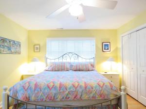 une chambre avec un lit avec une couette colorée et une fenêtre dans l'établissement Cedar Cottage, à Cape May Point