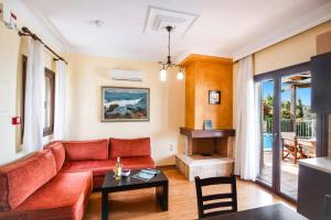a living room with a red couch and a piano at Villa Erato Nikitas by Villa Plus in Agios Nikitas