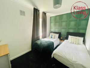 a bedroom with two beds and a green wall at Mitchell Apartment by Klass Living Coatbridge in Coatbridge +3 photos