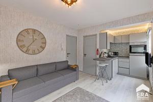 a living room with a couch and a clock on the wall at Studio Cosy & Zen à Coxyde Dog-friendly in Koksijde +26 photos