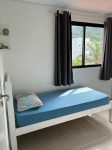 a bed in a room with a window at APTO 38- Enseada- Próximo ao Pão de Açúcar in Guarujá +10 photos