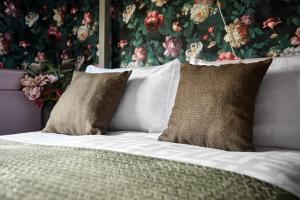 a bed with two pillows and a floral wall at Carnbore House BnB in Bushmills