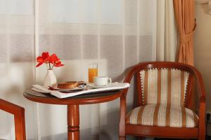 una mesa con un plato de comida y un jarrón de flores en ella en Hotel Moldova en Iaşi