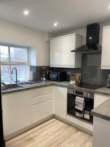 a kitchen with white cabinets and a stove top oven at The Lucia Apartments I - 2 Bedroom Town Centre Apartment - Contractor Friendly - Free Parking - Full Kitchen - Washer Dryer - Spacious - Ideal for Work Stays in Huntingdon +29 photos