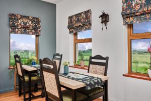 a dining room with a table and chairs and windows at Carnbore House BnB in Bushmills