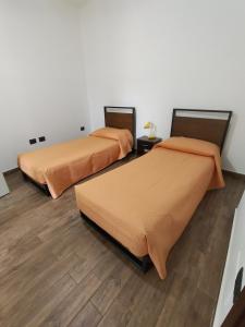 two beds in a room with wooden floors at B&B Vista Mare in Palmi