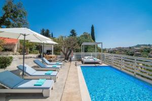 a pool with lounge chairs and an umbrella at Villa Observer by Villa Plus in Kipseli