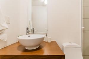 une salle de bain avec un lavabo blanc et des toilettes dans l'établissement CORAL Beachfront 2BDR with pool by Casa Paraiso, à Cancún