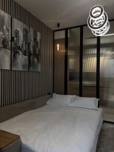 タシュケントにあるАренда квартиры #19 NRG U-Tower Rent an apartmentの白いベッドとシャンデリアのある寝室