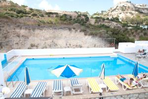 a swimming pool with lounge chairs and an umbrella at Archodia Studios in Kefalos