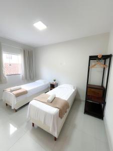 two beds in a room with white walls at Residencial Tijuco - Apto 204 in Diamantina