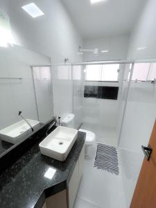 a white bathroom with a sink and a toilet at Residencial Tijuco - Apto 204 in Diamantina +33 photos