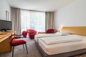 ズルツブルクにあるWaldhotel Bad Sulzburgのベッド2台と赤い椅子が備わるホテルルームです。