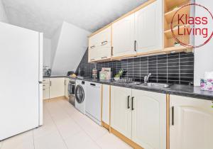 a kitchen with white cabinets and a washer and dryer at Rothesay House by Klass Living Coatbridge in Coatbridge