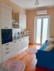 a kitchen with white cabinets and a blue couch at Residenza il Rododendro in Candelo