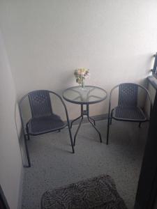 two chairs and a glass table with a vase of flowers at Apartament Exclusive in Rzeszów