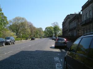 una strada con auto parcheggiate sul lato della strada di Terrace hotel a Edimburgo