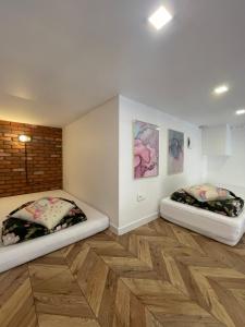 two beds sitting in a room with wooden floors at Loft z Antresolą i Balkonem w Centrum Łodzi Przystań Jednorożca Klimatyzacja Faktura in Łódź