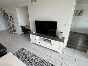 a living room with a flat screen tv on a white cabinet at City Stadium Apartment on the Riverfront 38 in Townsville