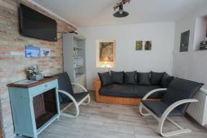 a living room with a couch and a tv at Fekete Gólya Fogadó Gemenc in Szekszárd