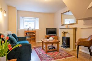 un salon avec un canapé bleu et une cheminée dans l'établissement Dove Cottage, à Hartington 7 autres photos