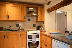 une cuisine avec une cuisinière et un bol de fruits sur le comptoir dans l'établissement Dove Cottage, à Hartington