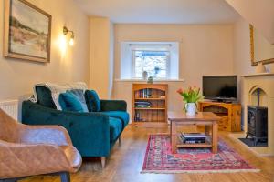 un salon avec un canapé bleu et une télévision dans l'établissement Dove Cottage, à Hartington
