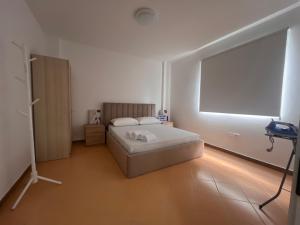 Una habitación blanca con una cama y una ventana. en Apartamente me qera Golem, en Golem