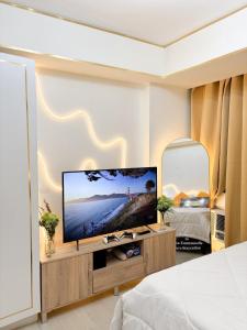 een slaapkamer met een grote flatscreen-tv aan de muur bij SM Bicutan Miami Flat in Manilla