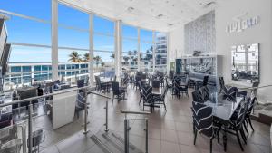 Un restaurante con sillas, mesas y ventanas. en SeaStays ~ Oceanfront Apartments, en Miami Beach