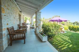 a patio with chairs and an umbrella on a house at Villa Danai by Villa Plus in Karyótikon