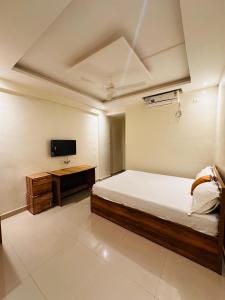una camera da letto con un letto, una scrivania e una TV di Hotel Nx Surya a Chākan