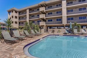 a hotel with a swimming pool in front of a building at 2 Bedroom/2 Bath, 3rd floor Oceanfront condo sleeps 6. Oceanfront deck and pool. in Fernandina Beach