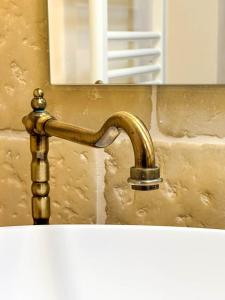 Un grifo de latón en un lavabo frente a un espejo. en Masseria Lu Monaco, en Melendugno