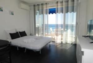 ein Schlafzimmer mit einem Bett und einem großen Fenster in der Unterkunft La caravelle in Juan-les-Pins