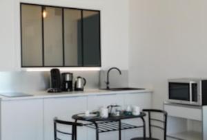 eine Küche mit zwei Tischen und einer Spüle und einer Mikrowelle in der Unterkunft La caravelle in Juan-les-Pins