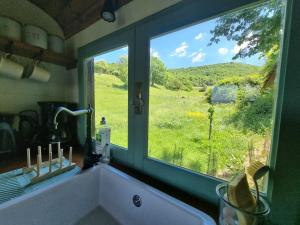 a kitchen window with a view of a field at Roulotte champêtre à la ferme in Rochefort-Sanson +3 photos
