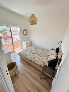 a bedroom with a bed and a chair and a window at Ton's Loft Caparica in Costa da Caparica