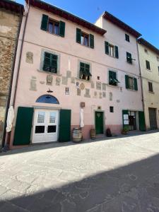 a large pink building with green doors and windows at Casa Vacanze Michelangelo in Laterina