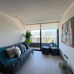 Una sala de estar con un sofá azul y una ventana grande. en Clínica Bupa y Davila Estadio Monumental y Mall Cenco Florida, en Santiago