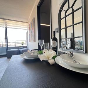 una mesa con dos platos blancos y una botella de vino en Clínica Bupa y Davila Estadio Monumental y Mall Cenco Florida, en Santiago