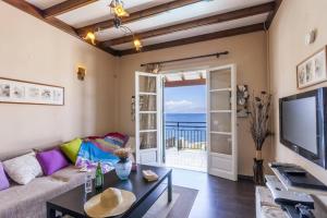 a living room with a couch and a tv at Villa Annie by Villa Plus in Kassiopi