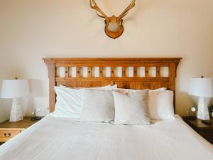a bed with white pillows and a deer head on the wall at Ski-In & Out, Top-Floor CB Condo, Panoramic Mountain View in Crested Butte