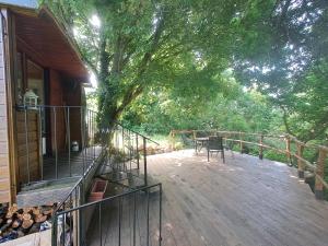 a wooden deck with a table and a tree at Roulotte champêtre à la ferme in Rochefort-Sanson