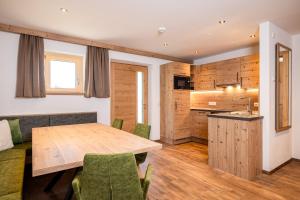 een keuken en eetkamer met een houten tafel en stoelen bij BEIM LOIS Edelweiss - AlpenLuxus Collection in Gerlos